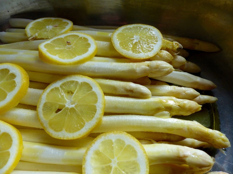 weiße Spargelstangen, noch roh, mit Zitronenscheiben garniert