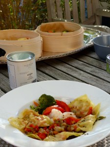 Ein asiatisches Gericht im Vordergrund, Bambus-Dampfkorb auf dem Tisch