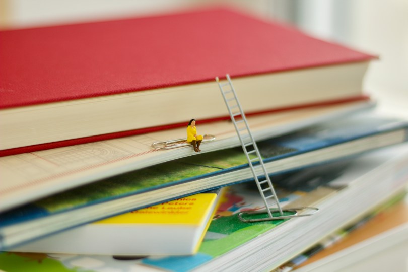 Miniaturfigur auf Bücherstapel Foto